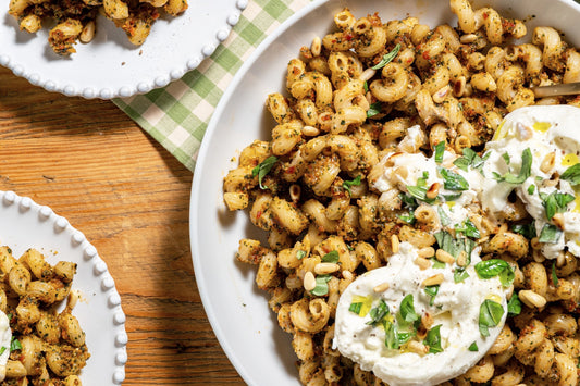 A serving platter with cavatappi with sun-dried tomato pesto and burrata.