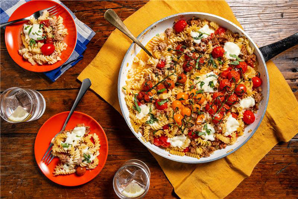 Pasta dish with vegetables and cheese in a pan on a wooden table