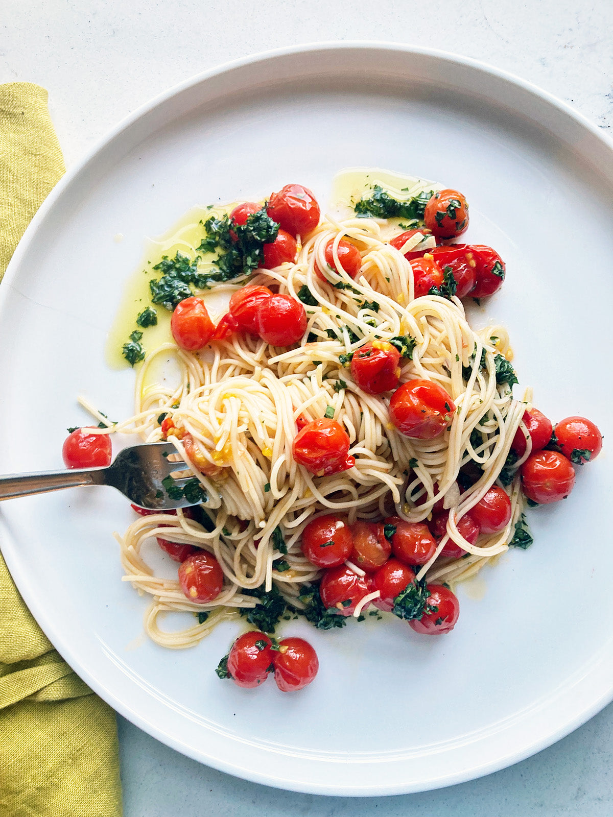 A plate of angel hair pasta with cherry tomatoes.