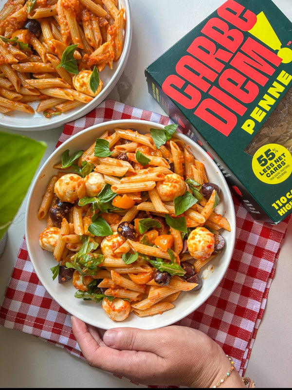 Two bowls of pasta with a Carbe Diem box or penne pasta.