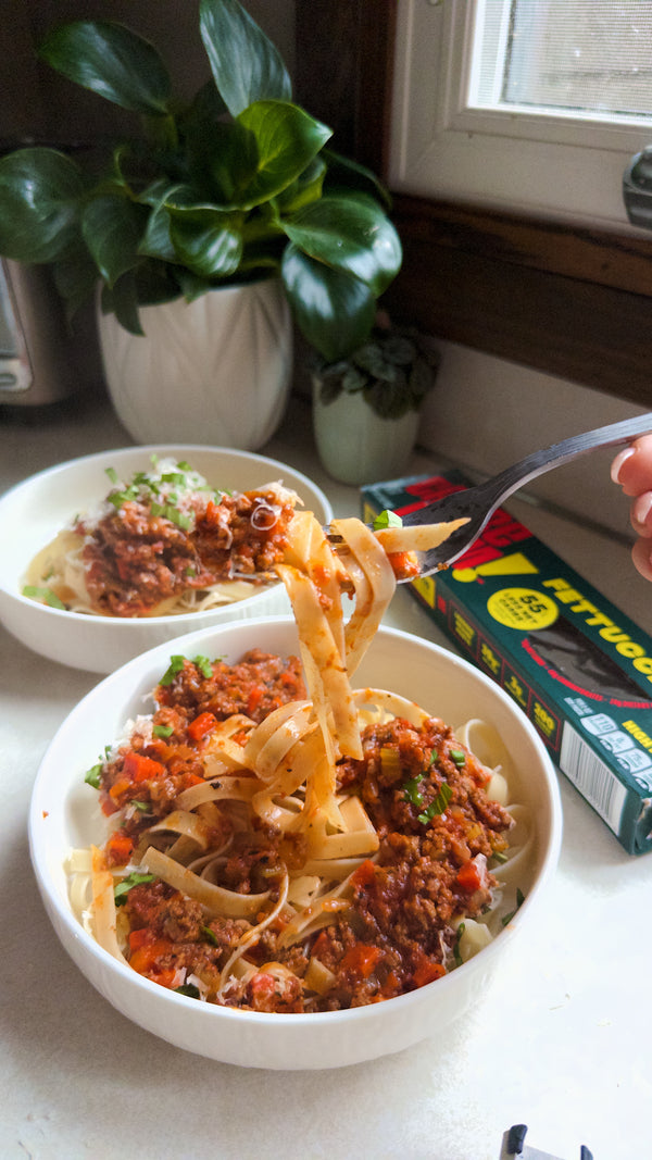 Fettuccine pasta dish being served with a fork, placed on a kitchen counter.