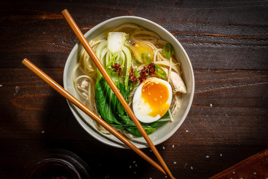 Chopsticks resting across a bowl of ramen made with Carbe Diem spaghetti.
