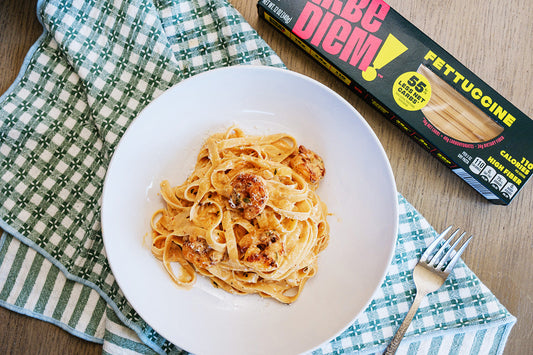 Plate of pasta with a box of Fettuccine noodles on a checkered cloth.