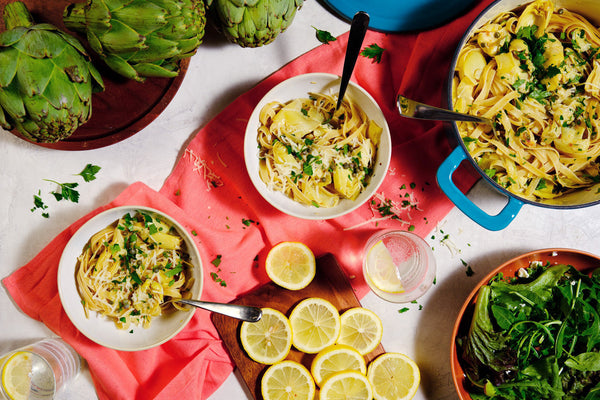 Two bowls next to a pot of One Pot Fettuccine with Lemon-Artichoke Sauce.