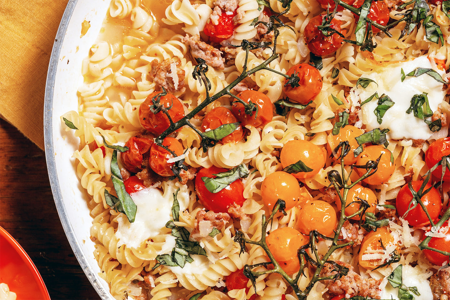 Pasta dish with cherry tomatoes and basil in a pan.