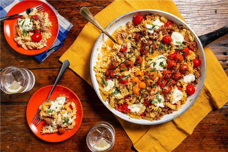 Pasta dish with vegetables and cheese in a pan on a wooden table