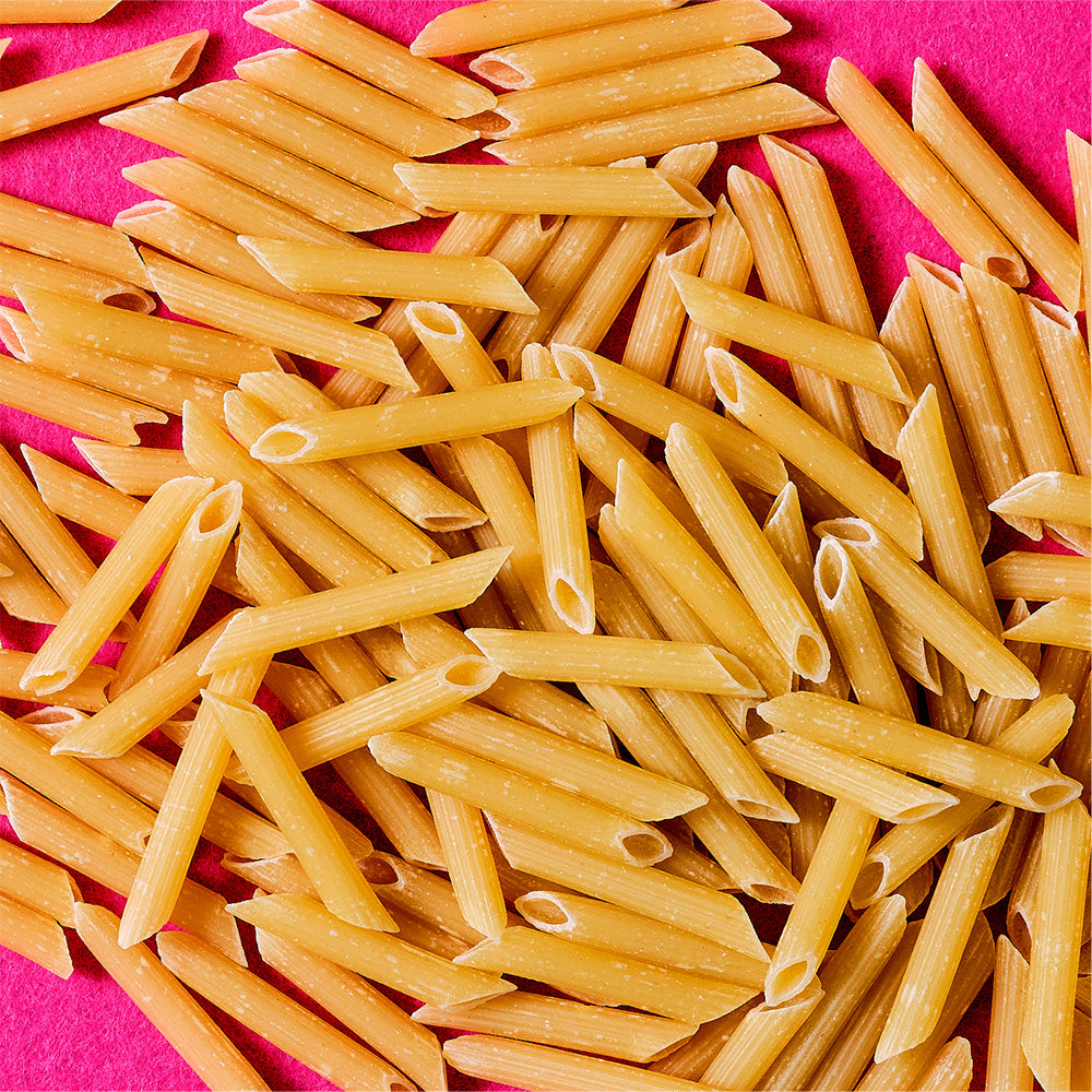 Penne pasta on a pink background