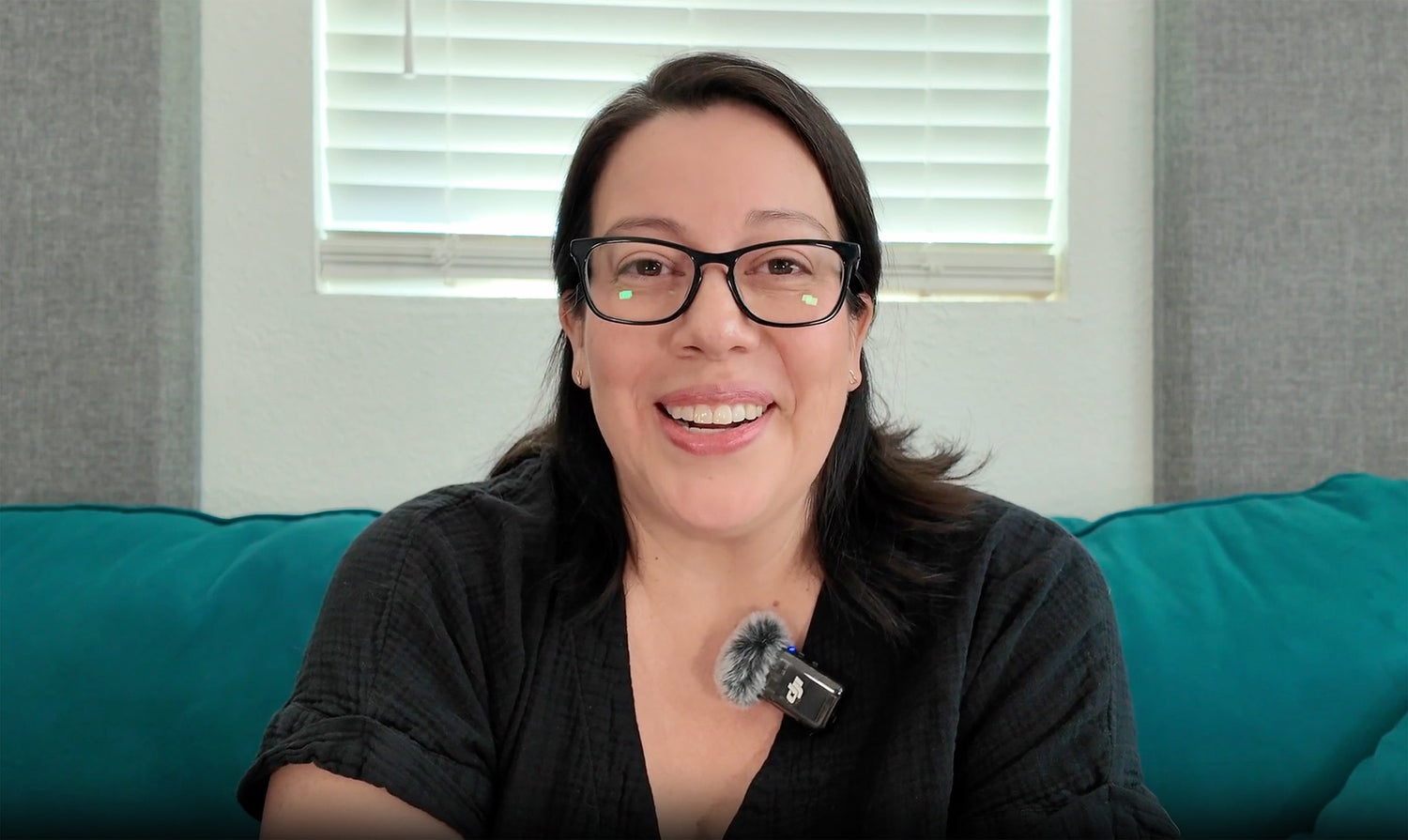 Woman with glasses and a microphone on a teal couch